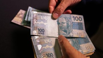 Outra ferramenta que vem facilitando a vida dos bandidos é o PIX Dinheiro Notas de 100 reais na mão de um pessoa - Reprodução/Agência Brasil