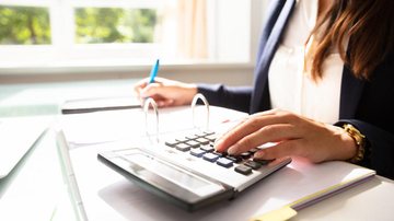 Organizar suas finanças pessoais é essencial financas Mulher escrevendo e usando calculadora - Reprodução / Internet