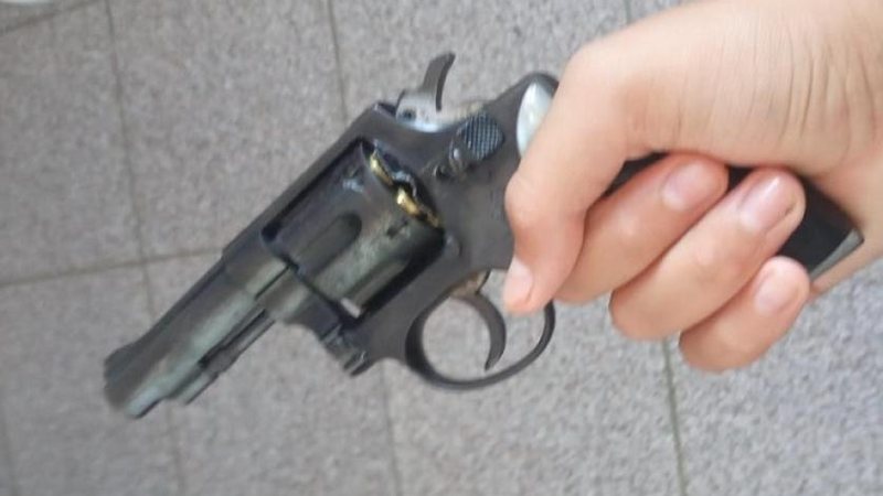 Jovem afirma que a arma foi jogada fora; policiais permanecem em busca do objeto Jovem divulga foto com revólver e faz ameaça de ataque à escola no litoral Revólver - Divulgação