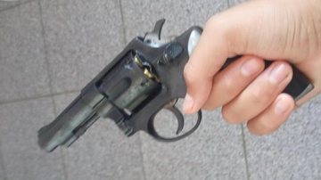 Jovem afirma que a arma foi jogada fora; policiais permanecem em busca do objeto Jovem divulga foto com revólver e faz ameaça de ataque à escola no litoral Revólver - Divulgação