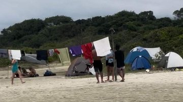 População afirma que os acampantes eram indígenas e concordam com a atitude deles Suposto acampamento é montado em praia e gera polêmica na internet Foto das barracas e do varal cheio de roupas instalados na areia da praia - Reprodução Facebook