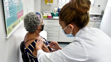 No sábado, moradores do Casqueiro terão a oportunidade de se imunizar APLICAÇÃO DE VACINA Profissional de saúde aplica uma injeção no braço de uma idosa - Prefeitura Municipal de Cubatão