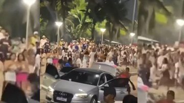 Homens cercam veículo de luxo e levam objetos de dentro do carro CONFUSÃO NO RÉVEILLON DA ENSEADA Uma multidão assiste um grupo de jovens atacando um veículo prata, na avenida da orla da praia
